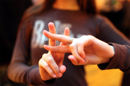 Woman crossing two finger on each hand to form a hashtag.