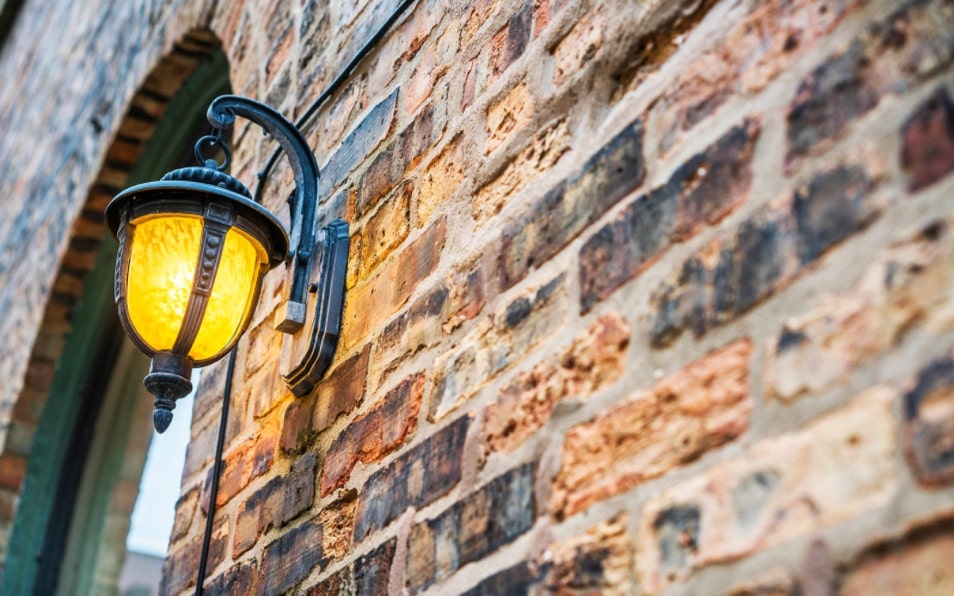 Brick wall with lamp hanging from it.